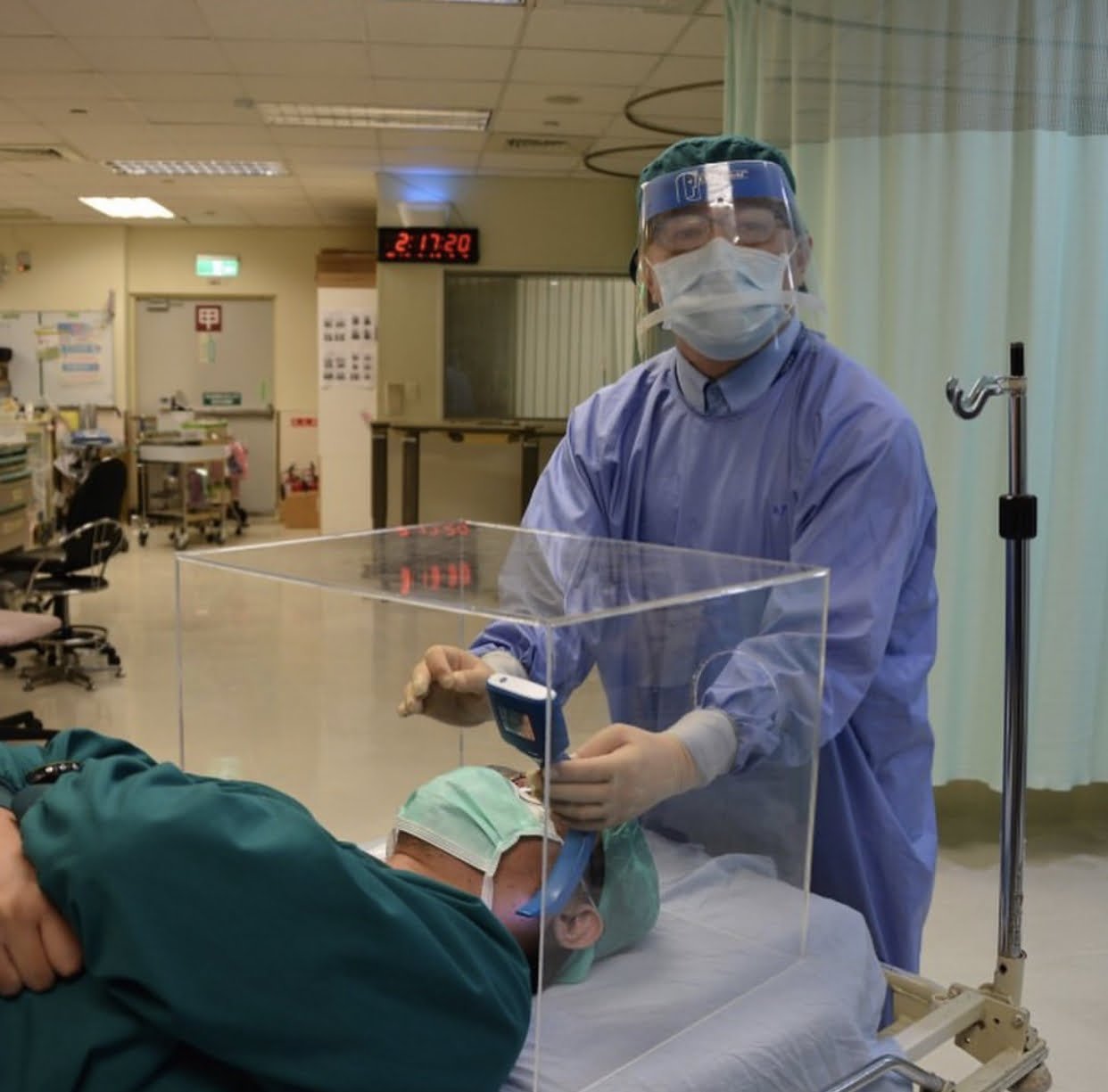 Doctor sosteniendo una caja acrílica de bioseguridad sobre un paciente.