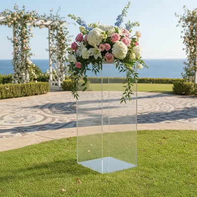 Pedestales en acrílico con arreglo floral en un evento al aire libre frente al mar.